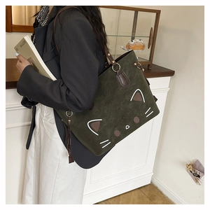 Detail of dark green tote bag with cat face design and premium suede texture