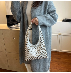 Détail du sac hobo blanc à rivets argentés porté par un mannequin en style décontracté