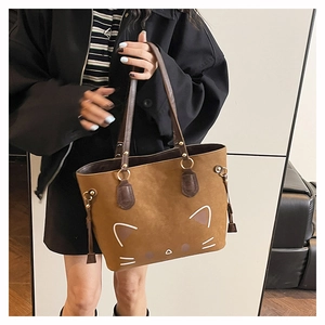 Close-up of brown cat-shaped tote bag with white whiskers and golden ring tassel detail
