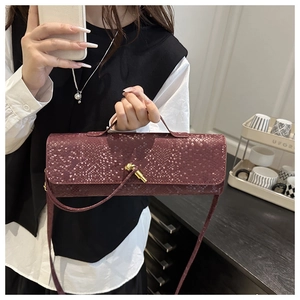 Gros plan d'un sac baguette bordeaux avec texture crocodile et boucle en métal doré