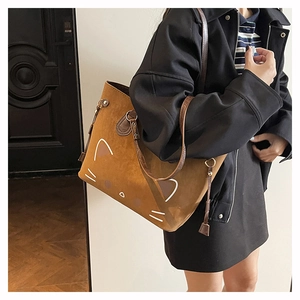 Detail view of large cat print tote bag in brown suede fabric on woman's shoulder