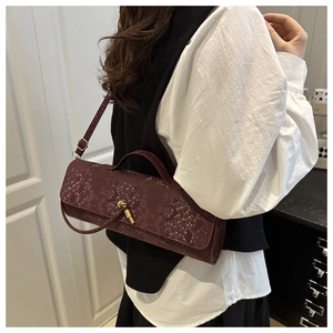 Détail du sac baguette bordeaux motif crocodile avec fermoir tournant doré à l'épaule
