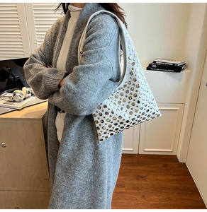 Détail du sac seau blanc en similicuir avec rivets argentés porté par un mannequin
