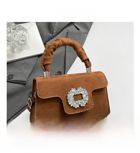 Detail shot of a brown suede handbag with sparkling rhinestone buckle and ruched handle
