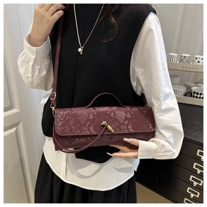 Vue détaillée du sac bordeaux motif crocodile avec boucle dorée en forme de nœud