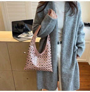 Close-up of pink leather hobo bag with silver studs held by a model in casual setting