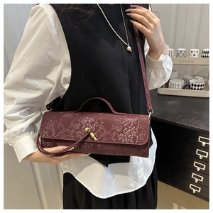Détail du sac à main bordeaux texture serpent avec fermoir nœud doré sur la bandoulière