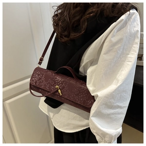 Détail du sac baguette bordeaux à motif crocodile avec fermoir doré sur modèle