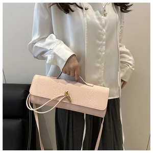 Détail d'un sac à main rose clair à motif crocodile avec fermoir doré et bandoulière