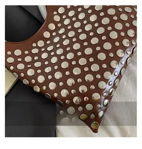Close-up of brown leather handbag with silver metallic studs in punk rock style details