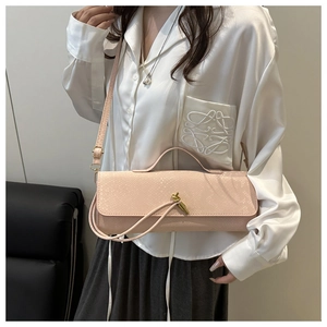 Détail du sac baguette rose à motif crocodile avec boucle en métal à nœud doré