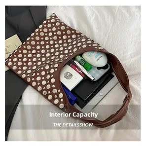 Detail showing high-capacity interior of brown leather punk rivet bag with essentials