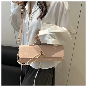Détail du sac bandoulière rose motif crocodile avec fermoir nœud doré sur mannequin