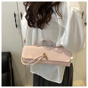 Détail d'un sac baguette en cuir rose à texture crocodile avec une boucle nœud dorée