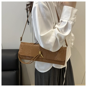 Vue détaillée de la texture serpent marron et du fermoir doré en nœud sur le sac