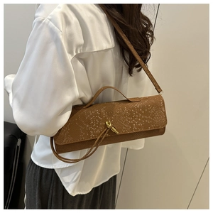 Détail de la texture crocodile rétro et boucle noeud doré sur le sac bandoulière marron