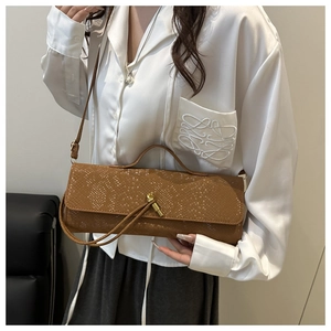 Sac à main marron texture crocodile porté avec une chemise blanche dans un décor épuré