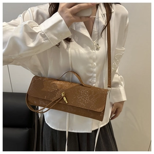 Détail de la texture crocodile marron et boucle dorée sur le sac baguette rétro