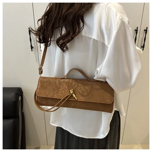 Détail du sac à main marron à texture crocodile avec boucle dorée et bandoulière fine
