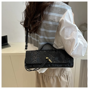 Détail du sac à main noir à motif serpent avec fermoir rotatif doré et texture raffinée