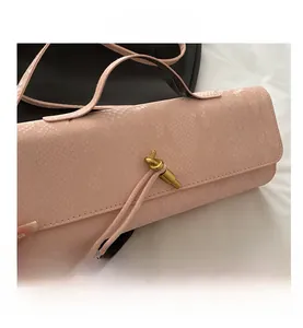 Détail du sac à main rose texture python avec fermoir nœud en métal et bandoulière