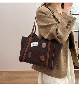 Detail of dark brown matte tote bag featuring vintage badges and puppy embroidery