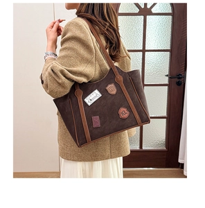 Detail of vintage tote bag with puppy patch on brown canvas shown on a model