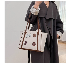 Close-up of retro cream tote bag featuring brown leather trim and stylish embroidered patches