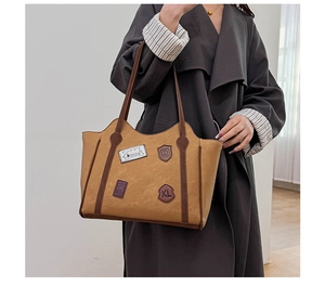 Close-up of vintage brown tote bag featuring decorative patches and leather badges