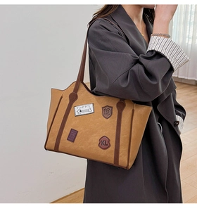 Detail of vintage tote bag with retro patches and brown shoulder strap on model