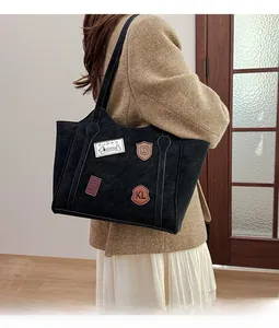 Detail of black tote bag featuring retro puppy patches and KL emblem on matte texture
