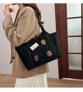Detail of vintage tote bag with decorative badges on textured black fabric material