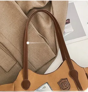 Top view of a textured light brown tote bag with vintage badge and slim dark handles