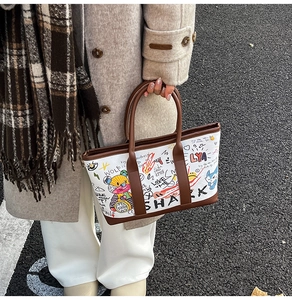 Detail of colorful graffiti print and brown leather handles on a large winter tote bag