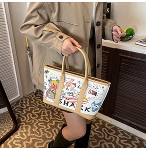 Detail of cartoon graffiti tote bag featuring leather handles and artistic sketches