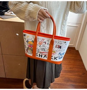Detailed close-up of cartoon graffiti canvas tote with orange straps held by model