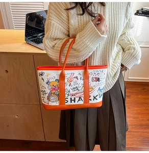 Detail of graffiti bear canvas tote with orange leather handles in a home setting