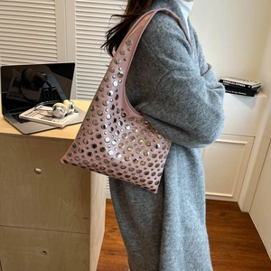 Sac seau rose à rivets argentés et large bandoulière porté par un mannequin élégant