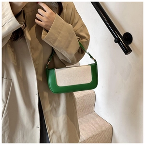 Detail of green leather and cream canvas patchwork crossbody bag on a model