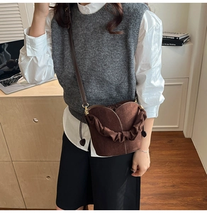 Deep brown suede bucket bag with petal-style handle and heart pendant detail