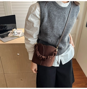 Brown suede bucket bag with pleated handle and thin strap in an office commute scene