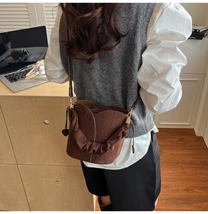 Detail of dark brown matte bucket bag with pleated handle and drawstring closure
