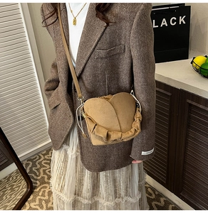 Detailed view of brown suede petal-shaped bucket bag with elegant pleated handle texture