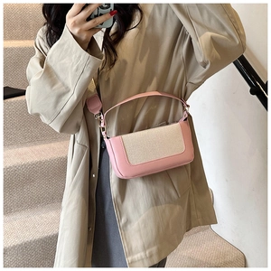 Dettaglio della borsa a tracolla patchwork rosa e beige con ampia fascia su un trench