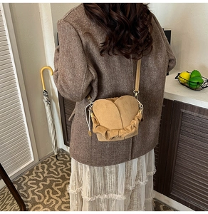 Brown suede bucket bag with petal fold design worn by model in a vintage aesthetic