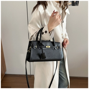 Détail d'un sac à main noir en cuir grainé avec fermoir doré et bandoulière amovible