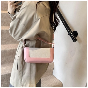 Detail view of pink leather and beige canvas patchwork shoulder bag with sleek shoulder strap
