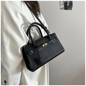 Détail du sac noir motif litchi avec fermoir doré et bandoulière amovible
