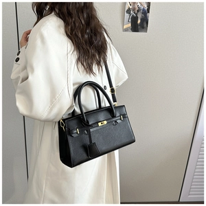 Détails d'un sac en cuir noir grainé litchi avec boucle dorée et bandoulière