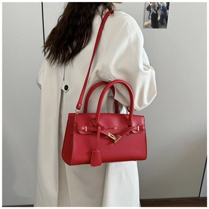 Détail du sac à main rouge en cuir grainé avec fermoir doré et bandoulière amovible